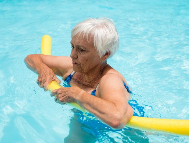Senior woman swimming with inflatable tube in the pool